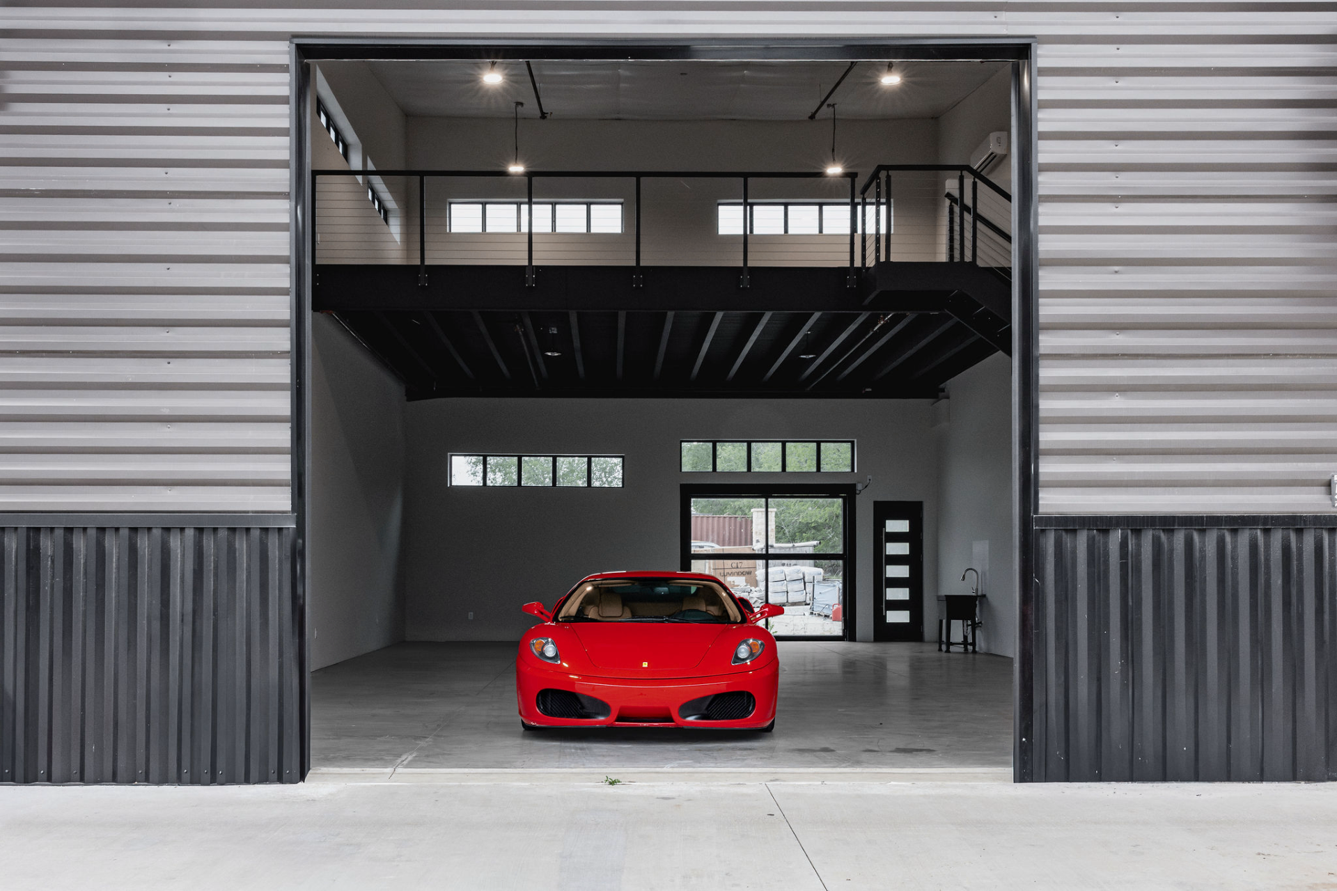 Red Ferrari parked inside a GOTA Autominium with a 2nd story above