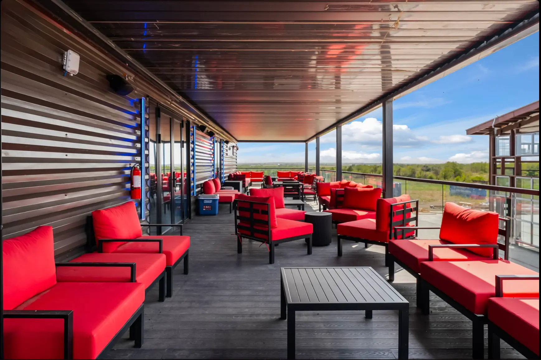 Covered rooftop deck with red lounge seating and hill country views