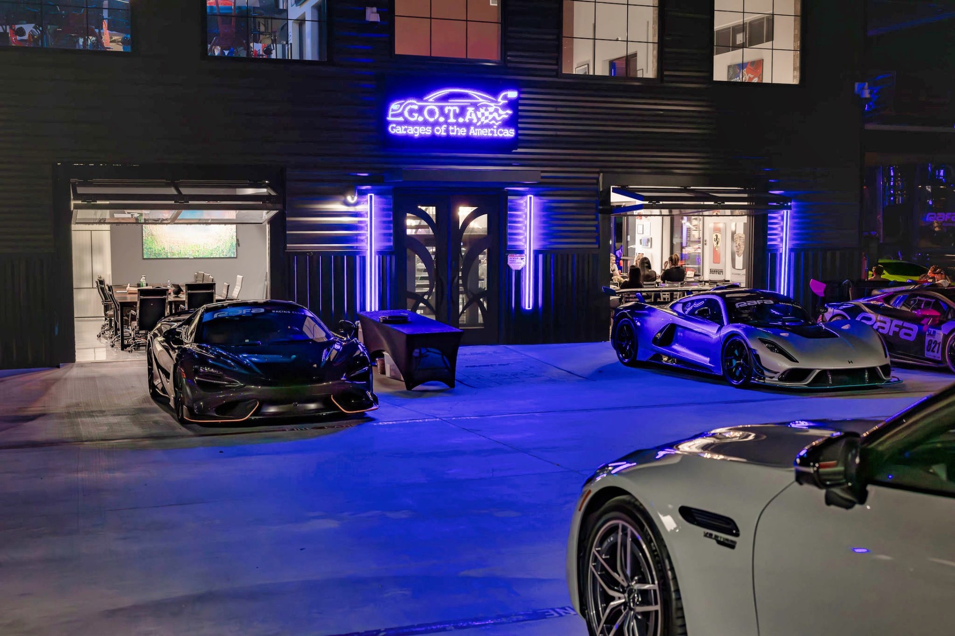 RAFA Racing Club supercars parked in front of the GOTA neon sign at night